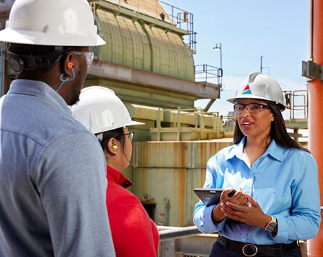Woman in hardhat speaking to other workers at a power plant